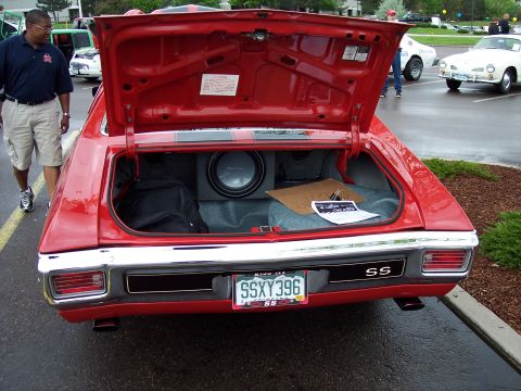 1972 Ford Ranchero - The rear of a red muscle car is shown with the trunk open, revealing a subwoofer and other items inside.