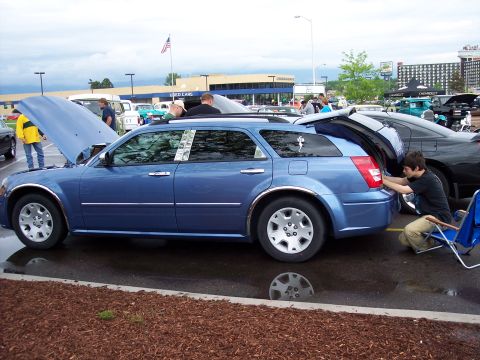 1972 Ford Ranchero - A blue station wagon is parked with its hood open, while someone closes the trunk in a parking lot.