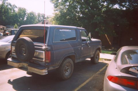 1982 Ford Bronco - This 1980s Ford Bronco is seen from a three-quarter front view, parked next to other vehicles.