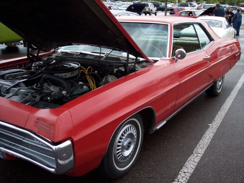 1972 Ford Ranchero - A red car with its hood open, revealing the engine. The vehicle's body style suggests it is from around 1970.