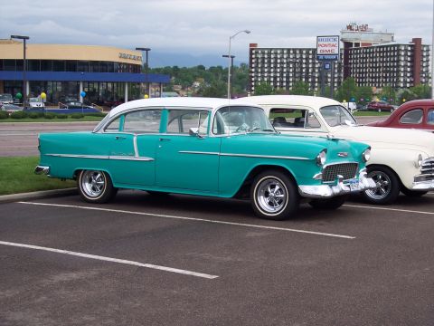 1972 Ford Ranchero - A teal and white 1955 Chevrolet Bel Air sedan is parked next to other vehicles in a lot.