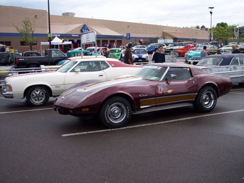 1972 Ford Ranchero - Maroon 1975 Corvette C3 with gold stripes and decals, parked next to a white Ford coupe in a parking lot.