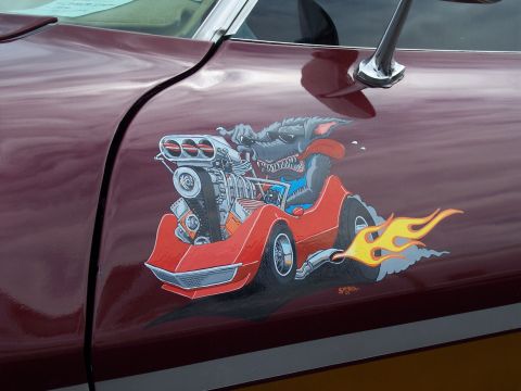 1972 Ford Ranchero - A cartoon rat in a hot rod with flames is painted on the side of a maroon vehicle.