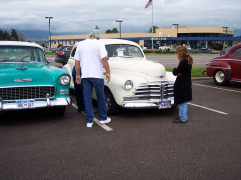 1972 Ford Ranchero - Two classic cars, a teal 1955 Chevrolet and a cream 1949 Chevrolet, are displayed at a dealership.