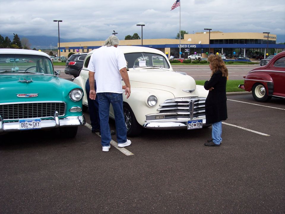 Teal 1955 Chevrolet and cream 1949 Chevrolet parked at a used car lot