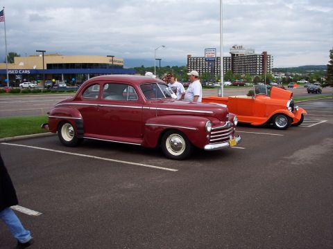 1972 Ford Ranchero - Two vintage automobiles are parked side-by-side in a parking lot under a cloudy sky.