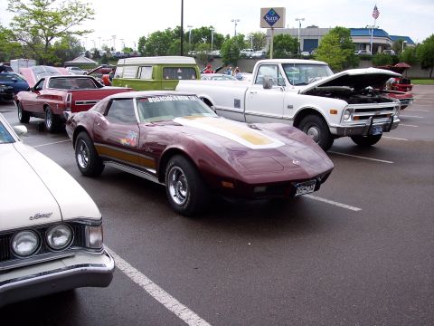 1972 Ford Ranchero - A maroon sports car with a yellow stripe and flame decals is parked in a lot with other vehicles.