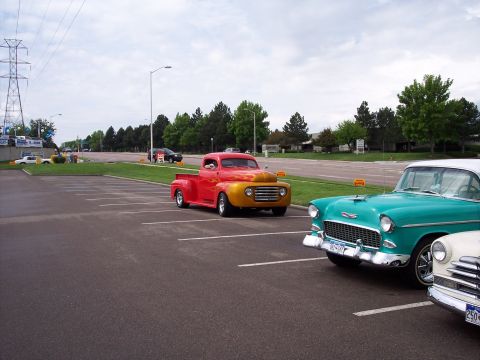 1972 Ford Ranchero - A vintage red and yellow pickup truck is parked in a lot next to other classic cars.
