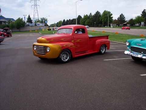 1972 Ford Ranchero - This custom pickup truck features a striking red and gold flame paint job, with a prominent grille and classic body lines.