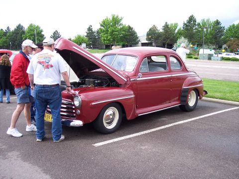 1972 Ford Ranchero - A classic red coupe, likely from the 1940s, is displayed with its hood open, attracting attention from onlookers.