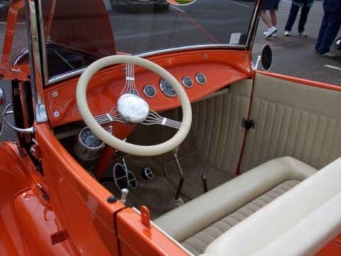 1972 Ford Ranchero - The interior of an orange hot rod features a white steering wheel and tan upholstered seats.