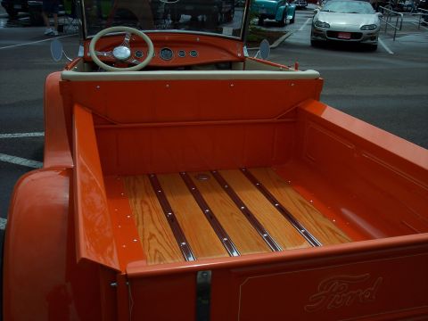 1972 Ford Ranchero - The Ford script on the tailgate of this orange pickup truck is visible, but the year is not identifiable from the image.