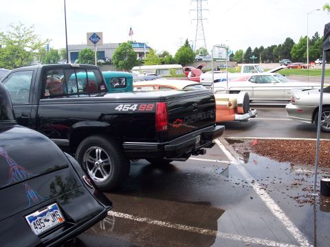 1972 Ford Ranchero - A black Chevrolet pickup truck is parked in a lot with other vehicles, including a classic car.