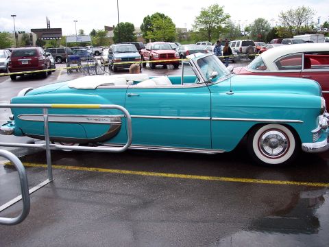 1972 Ford Ranchero - A turquoise convertible with chrome trim and whitewall tires is parked in a lot with other vehicles.