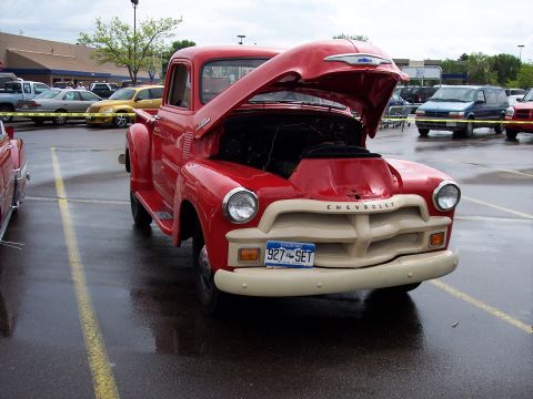 1972 Ford Ranchero - A classic red Chevrolet pickup truck is parked with its hood open in a wet parking lot.