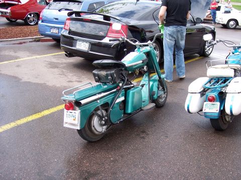 1972 Ford Ranchero - Two vintage scooters are parked on a wet asphalt lot next to cars.