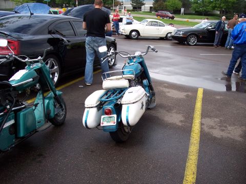 1972 Ford Ranchero - A blue and white motorcycle is parked in a lot with other vehicles, including a black sedan and a white classic car.