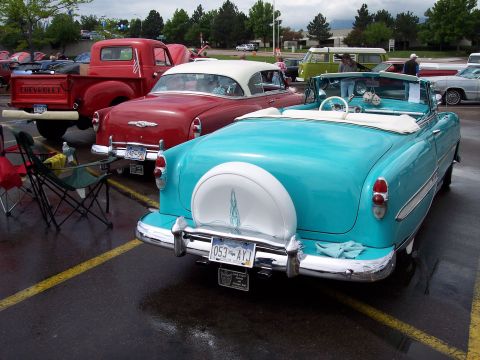 1972 Ford Ranchero - A turquoise convertible with a continental kit and white top is parked in a lot with other classic vehicles.