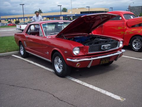 1972 Ford Ranchero - A red 1965 Ford Mustang coupe is parked with its hood open, next to a red hot rod truck.