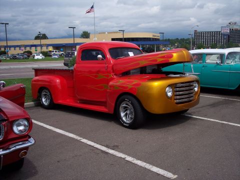 1972 Ford Ranchero - This customized pickup truck features flame graphics and an open hood, parked next to another vintage vehicle.