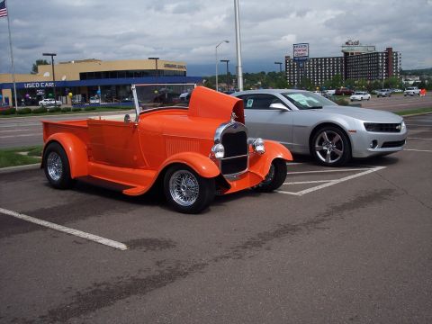 1972 Ford Ranchero - An orange hot rod pickup truck is parked in a lot next to a modern silver car.
