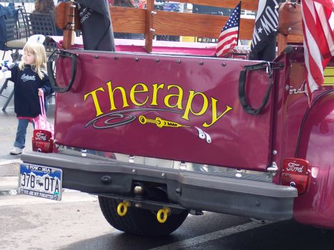1972 Ford Ranchero - The tailgate of a pickup truck features the word 'Therapy' and a graphic of a syringe, with a young girl standing nearby.