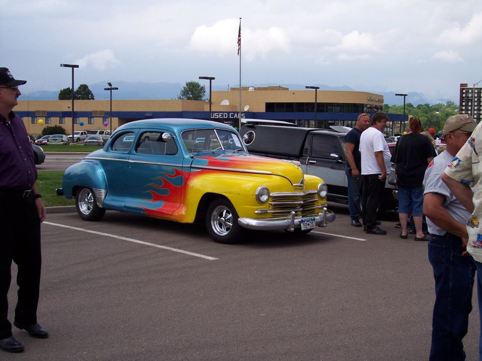 Blue and yellow coupe with flame decals parked in a lot, front quarter view