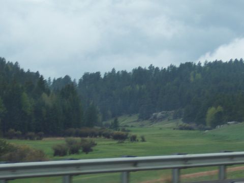 1972 Ford Ranchero - A view of a valley with trees and a cloudy sky, taken from a moving vehicle.