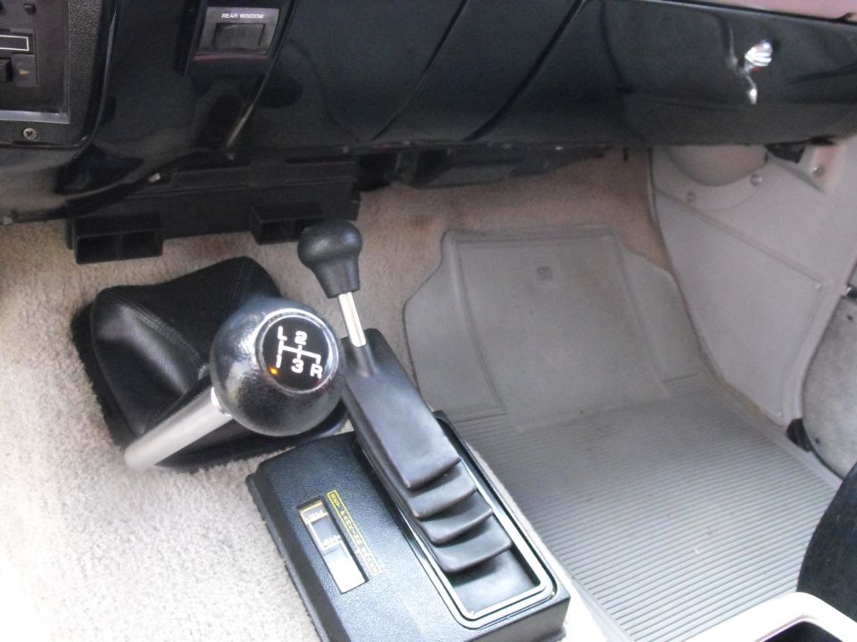 Vehicle interior showing a floor shifter, a 4-speed manual gear selector, and floor mats