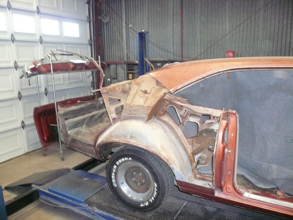 1975 Ford Ranchero body on lift, undergoing repairs. Rear quarter panel and wheel well visible