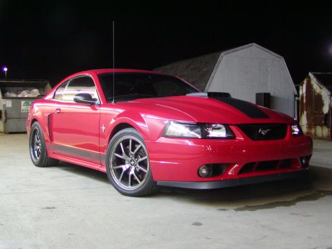 2004 Ford Mustang - A red 2004 Ford Mustang is parked outdoors at night, black racing stripes and an aftermarket hood scoop.