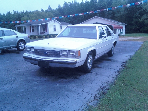 White 1987 Ford Crown Victoria LTD sedan parked on cracked asphalt, front 3/4 view