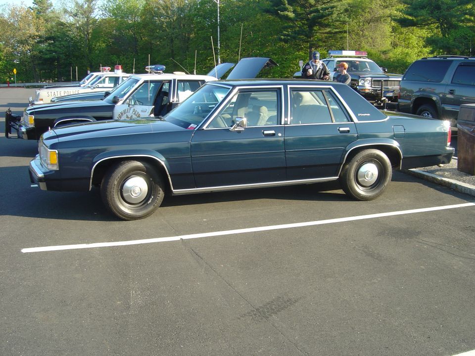 dark blue sedan parked next to police cars