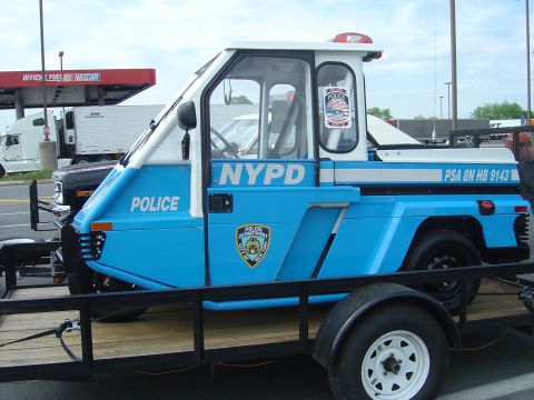 2001 Ford Crown Victoria - A blue and white NYPD vehicle is transported on a trailer, displaying police markings and identification numbers.