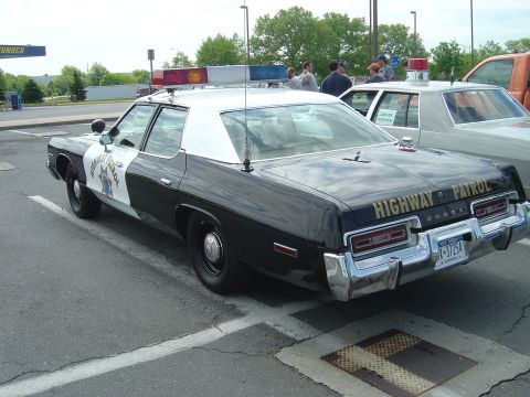 2001 Ford Crown Victoria - This Dodge highway patrol car features a two-tone paint scheme and a prominent light bar on the roof.