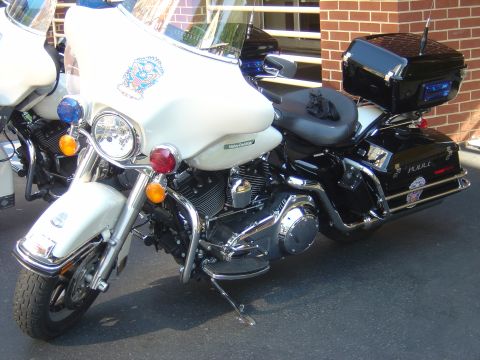 2001 Ford Crown Victoria - A police motorcycle is parked next to another motorcycle, with a brick building in the background.