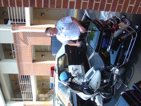 2001 Ford Crown Victoria - A police officer stands next to a patrol car and motorcycle.