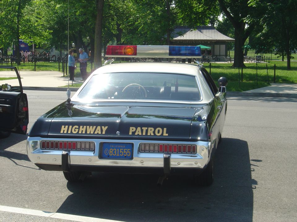 Rear view of black highway patrol car with light bar and California license plate 831555