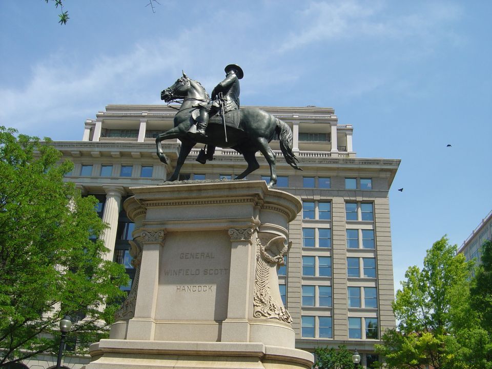 Statue of General Winfield Scott Hancock on horseback, with a building and trees in the background