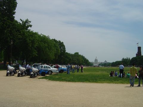 2001 Ford Crown Victoria - A line of police motorcycles and cars are parked on a lawn, with the Washington Monument and Capitol Building visible in the background.