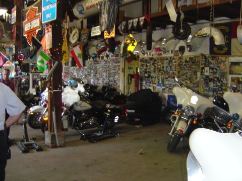 2001 Ford Crown Victoria - A collection of motorcycles are parked in a garage adorned with numerous signs and photographs.