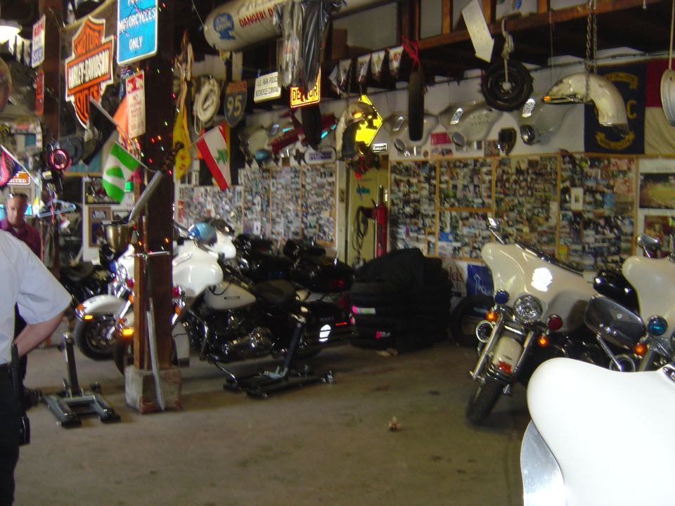 Motorcycles parked inside a cluttered garage with memorabilia on walls
