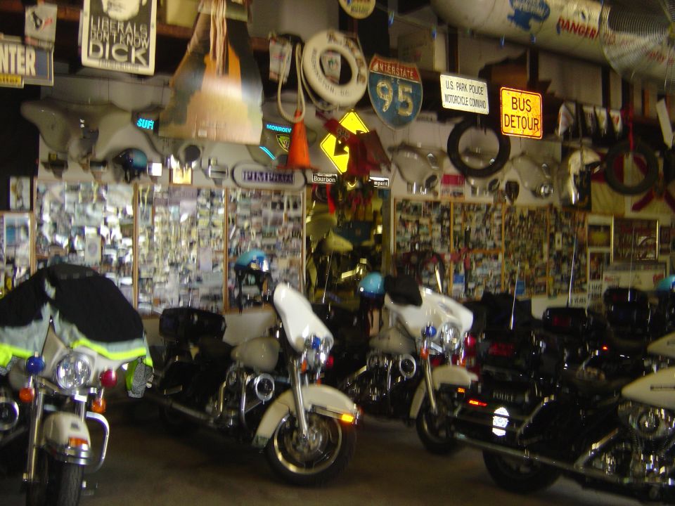 Several police motorcycles parked inside a garage with walls covered in memorabilia