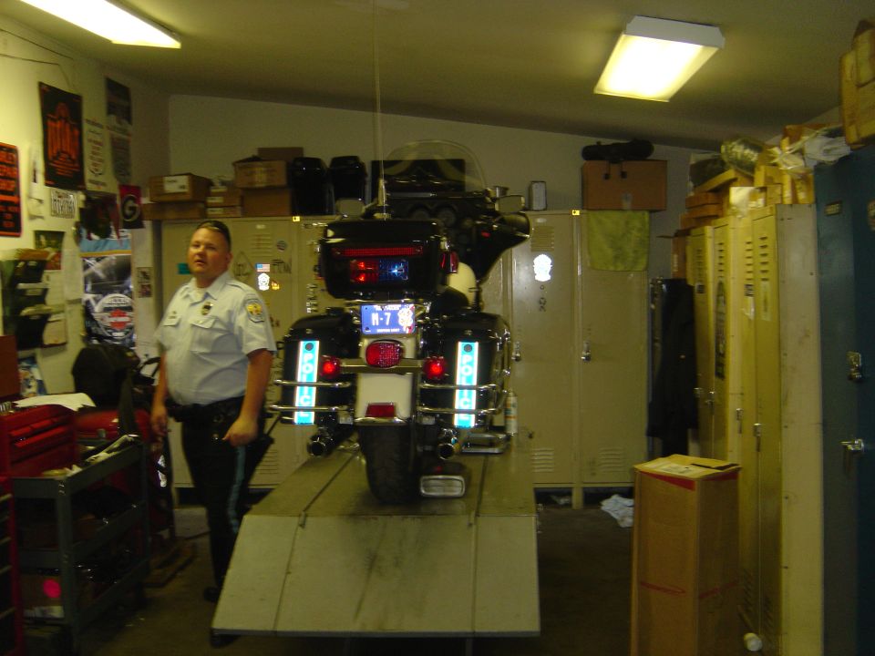 Police motorcycle on a ramp, rear view. Black with reflective tape and a license plate reading B-7