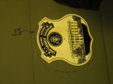 2001 Ford Crown Victoria - A U.S. Secret Service Uniformed Division badge an illustration of the White House is displayed on a surface.