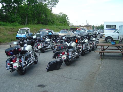 2001 Ford Crown Victoria - A fleet of police motorcycles and cars are parked together in an outdoor lot.