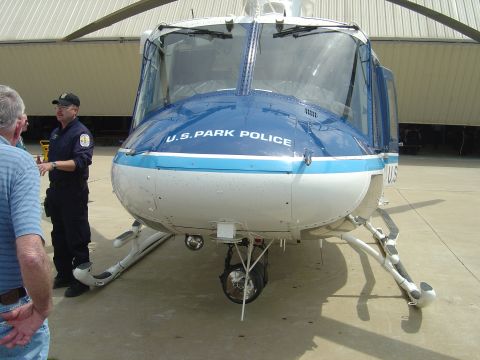 2001 Ford Crown Victoria - A U.S. Park Police helicopter is parked on a tarmac, with two individuals observing it.