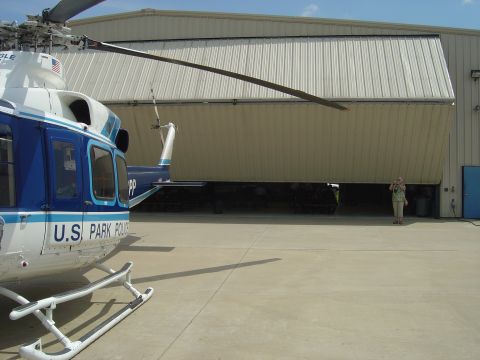 2001 Ford Crown Victoria - A U.S. Park Police helicopter is parked outside a hangar, with another helicopter visible inside the open hangar.