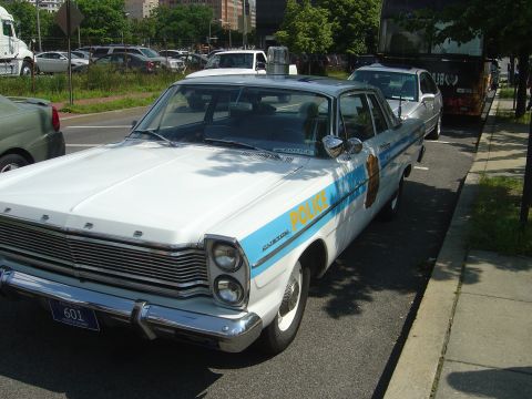 2001 Ford Crown Victoria - This 1966 Ford Custom police car features a distinctive white and blue livery with 'POLICE' text visible on the side.