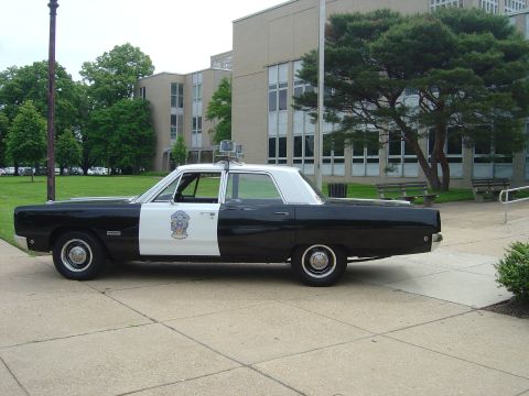 2001 Ford Crown Victoria - Side view of a vintage police car with a two-tone paint scheme and light bar.